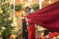 Little Santa Claus pulling huge bag of gifts on Christmas background. Santa helper carrying sack full of gifts. Funny Royalty Free Stock Photo
