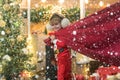 Little Santa Claus pulling huge bag of gifts on Christmas background. Santa helper carrying sack full of gifts. Child in Royalty Free Stock Photo