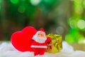 Little santa claus with red heart shape and group of giftbox on white cotton with green boken bacjground. Christmas concept Royalty Free Stock Photo