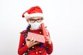 Little santa helper holding christmas gift. Child wearing safety mask. Christmas shopping and sales Royalty Free Stock Photo