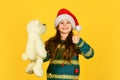 Little santa with toy. small girl santa claus hat red background. prepare for new year party. christmas favorite holiday