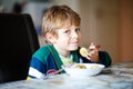 Little school boy eating pasta indoor in a canteen. Royalty Free Stock Photo