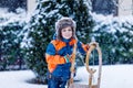 Little school boy having fun with sleigh ride during snowfall. Hapy child sledding on snow. Preschool kid riding a