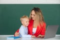 Little school child son using laptop with mother. Elementary school classroom. Teacher and schoolchild pupil in class Royalty Free Stock Photo