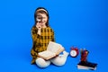 Little school girl in checkered dress holding magnifier and smiling Royalty Free Stock Photo