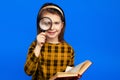 Little school girl in checkered dress holding magnifier and smiling Royalty Free Stock Photo