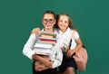 Little school girl with pile of books. Teen student carry a book. Hard to study. Sisters hugging and ready to school. Royalty Free Stock Photo