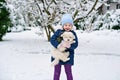 Little school girl playing with little maltese puppy outdoors in winter. Happy child and family dog having fun with snow Royalty Free Stock Photo