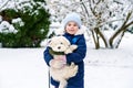 Little school girl playing with little maltese puppy outdoors in winter. Happy child and family dog having fun with snow Royalty Free Stock Photo