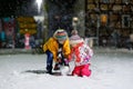 Little school kid boy and cute toddler girl sitting together playing with snow on winter night. Siblings, brother and Royalty Free Stock Photo