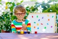 Little school kid boy with glasses holding lots of brushes and c Royalty Free Stock Photo