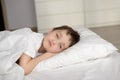 Little schoolboy resting in white bed with eyes open Royalty Free Stock Photo