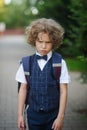 Little schoolboy stands in the school yard with an angry expression on his face . Royalty Free Stock Photo