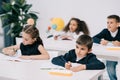 Little schoolchildren sitting at desks and writing in exercise books Royalty Free Stock Photo