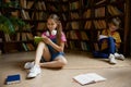 Little schoolchildren spending time at home library Royalty Free Stock Photo