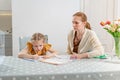 A little schoolgirl does her homework. mom sits next to her and angry