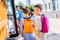 little schoolgirl entering school bus with classmates while teacher standing Royalty Free Stock Photo