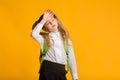 Little Schoolgirl Feeling Bad Touching Head, Yellow Background