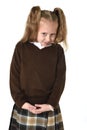 Little schoolgirl girl with beautiful blonde hair in school uniform looking shy and timid Royalty Free Stock Photo