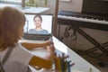 Little schoolgirl listens to teacher at videocall via laptop at table in light room Royalty Free Stock Photo