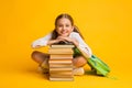 Little Schoolgirl Smiling Sitting At Stack Of Books, Yellow Background