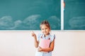 Little schoolgirl stands near the chalkboard, back to school, children education