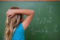 Little schoolgirl thinking while scratching the back of her head