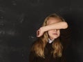 Little schoolgirl in uniform covering her face with her arm crying sad victim of bullying at school