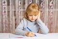 Little schoolgirl writes with a pen in a notebook. Distance learning. The child is doing homework