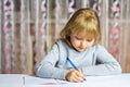 Little schoolgirl writes with a pen in a notebook. Distance learning. The child is doing homework