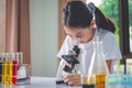 little scientist looking through a microscope and test tubes filled with chemicals for learning about science and experiments Royalty Free Stock Photo