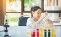 little scientist looking through a microscope and test tubes filled with chemicals for learning about science Royalty Free Stock Photo