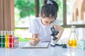 little scientist looking through a microscope and test tubes filled with chemicals for learning about science and experiments Royalty Free Stock Photo