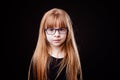 Little serious blond girl with glasses on a black background