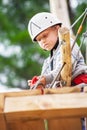 Little serious boy attaches safety cords on the rope track