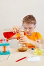 Little serious boy in safety goggles studies chemical practice in laboratory