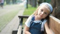 Little serious child girl sitting alone on a bench in summer park Royalty Free Stock Photo