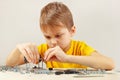 Little serious engineer plays with metal constructor at table