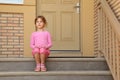 Little serious girl sits on stairs near door Royalty Free Stock Photo