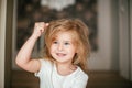 Little shaggy blonde baby girl with a hand up is smiling after her morning awaking Royalty Free Stock Photo