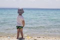 A little shy boy with hat standing in the sand near water and lo Royalty Free Stock Photo