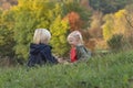 Little siblings resting in nature. Blond boy and girl sit on grass and eat apples. Children on picnic on autumn day