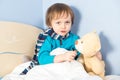 Little sick baby boy checking teddy bear's body temperature