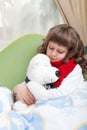 Little sick girl with scarf embraces toy bear Royalty Free Stock Photo