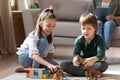 Little sister and brother playing with toys together on floor Royalty Free Stock Photo