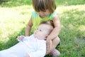 Little sisters in the backyard. Smiling kids sitting on grass in summer. Children in family: toddler and baby portrait Royalty Free Stock Photo