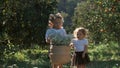 Little sisters carry white flowers in basket in the garden