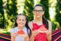 Little sisters eating watermelon slices in the garden sitting on a hammock