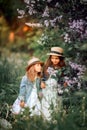 Little sisters outdoor portrait near lilac tree