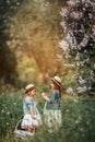 Little sisters outdoor portrait near lilac tree